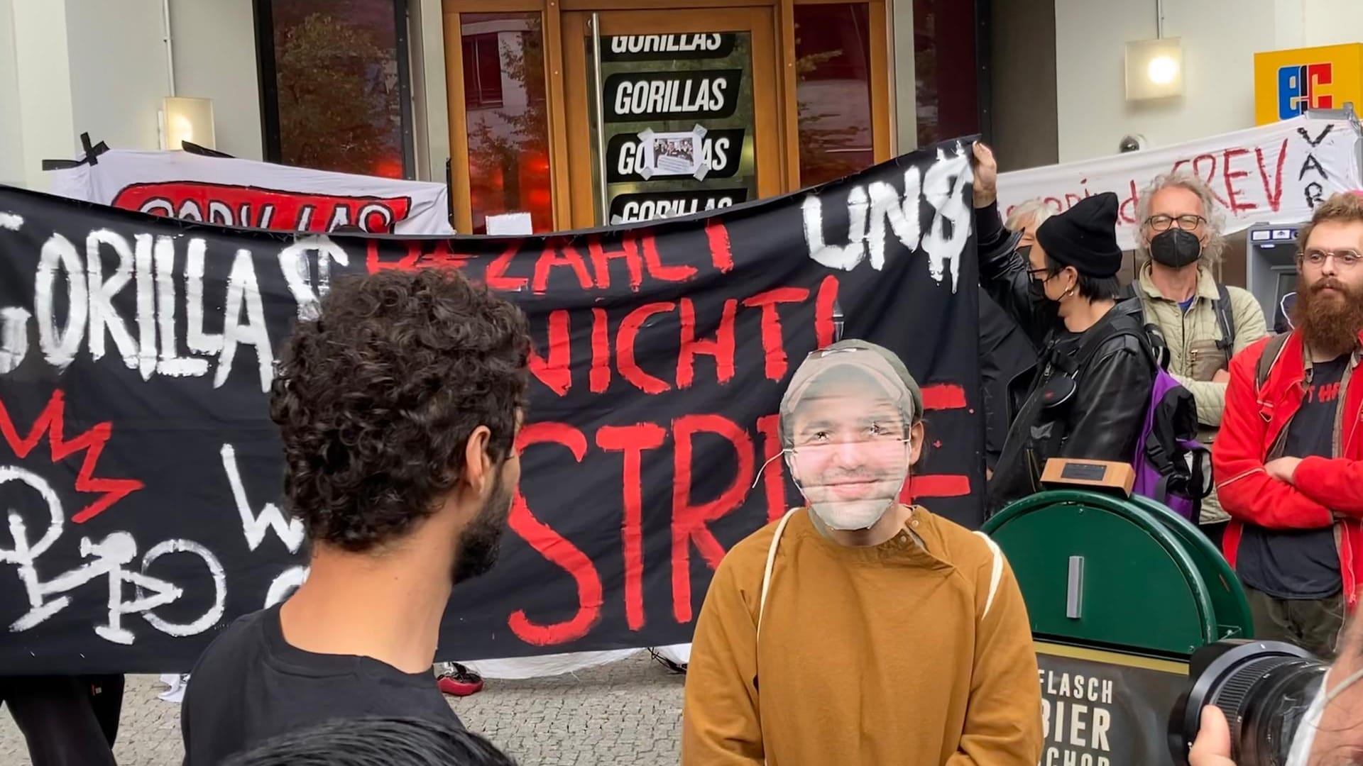 Ein Kurier mit Sümer-Maske beantwortet die Fragen der Demonstranten: Niemand glaubt, dass sich der Unternehmensgründer den Protesten stellen wird.