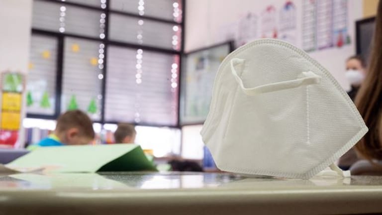 Eine Maske auf einem Schultisch (Symbolbild): Momentan müssen Schülerinnen und Schüler in Berlin keinen Mund-Nasen-Schutz tragen.