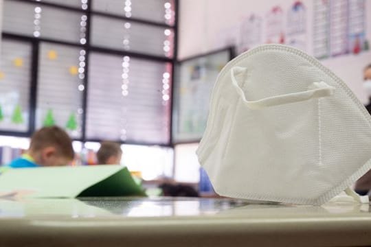 Eine Maske auf einem Schultisch (Symbolbild): Momentan müssen Schülerinnen und Schüler in Berlin keinen Mund-Nasen-Schutz tragen.