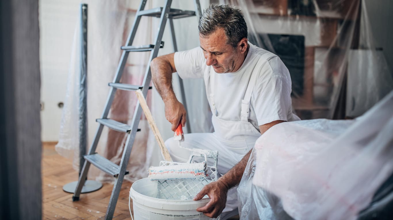 Ein Maler streicht eine Wohnung (Symbolbild): Manche Kunden wollen nur noch geimpfte oder genesene Handwerker ins Haus lassen.