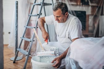 Ein Maler streicht eine Wohnung (Symbolbild): Manche Kunden wollen nur noch geimpfte oder genesene Handwerker ins Haus lassen.