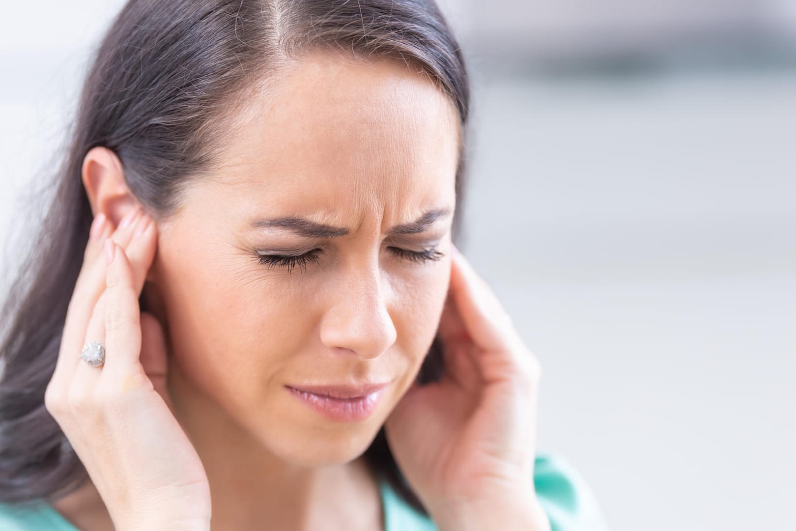 Eine Frau fasst sich an die Ohren. Stress kann das Hörvermögen negativ beeinflussen.