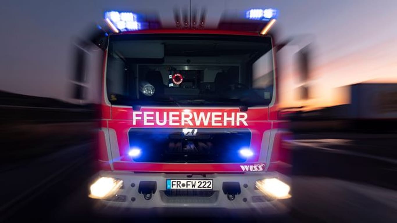 Ein Feuerwehrfahrzeug steht mit eingeschaltetem Blaulicht auf einer Straße (Symbolbild): In Hamburg hat ein Wohnhaus gebrannt.