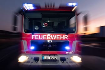 Ein Feuerwehrfahrzeug steht mit eingeschaltetem Blaulicht auf einer Straße (Symbolbild): In Hamburg hat ein Wohnhaus gebrannt.