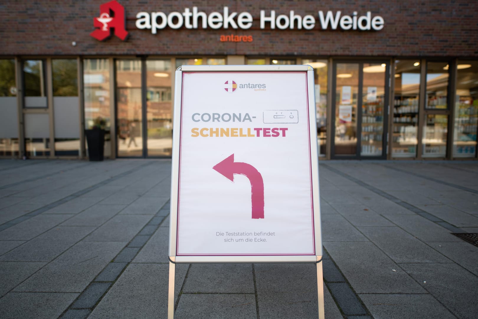 Ein Hinweisschild zu einem Testcenter steht vor einer Apotheke in Hamburg (Archivbild). Viele Ungeimpfte müssen bald bezahlen. Damit sollen sie zum Impfen bewegt werden