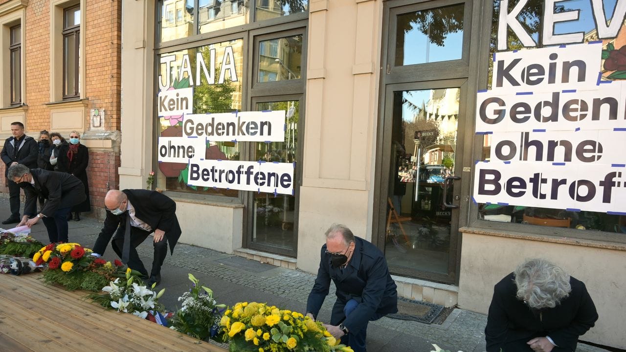 Halles Bürgermeister Egbert Geier (SPD, l) und Sachsen-Anhalts Ministerpräsident Reiner Haseloff (CDU, M) legen vor einem der Tatorte, einem Döner-Imbiss, Kränze für die Opfer des Anschlags vor zwei Jahren nieder.
