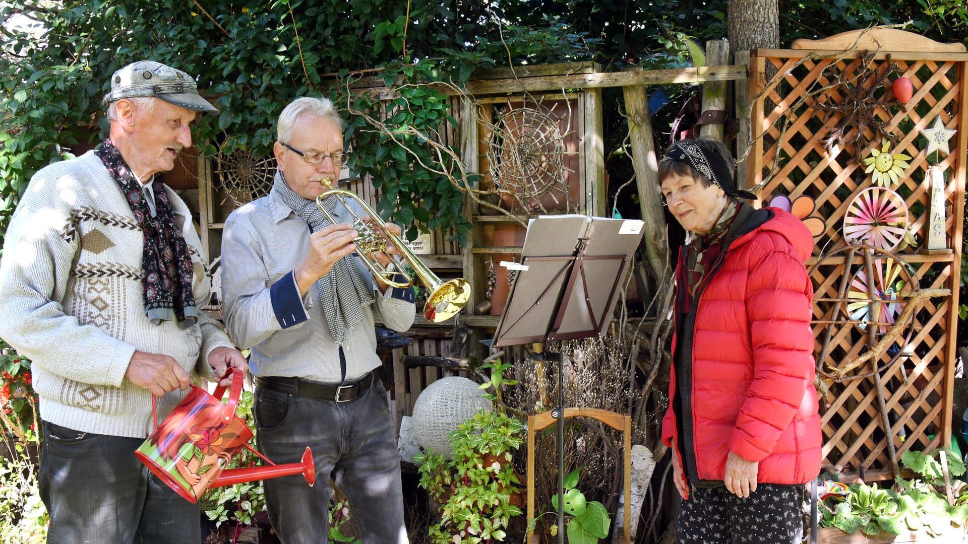 Fritz Hundt (l) und seine Frau Ingrid (r) stehen in "ihrem" Park neben dem Hobby Musiker Wolfram Hohnstädter, der jede Woche einmal mit seiner Posaune die Anwohner mit einem kleinen Konzert erfreut: In dem Treffpunkt für viele Bewohner aus dem Wohngebiet stehen auch Tische und Stühle zum Verweilen.