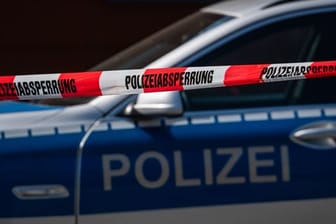 Ein Polizeiauto steht hinter einem Absperrband der Polizei (Symbolbild): Nahe Hamburg rätselt die Polizei zu einem mutmaßlichen Gewaltverbrechen.
