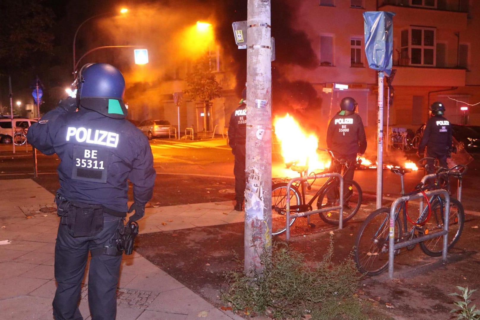 Polizisten stehen neben brennenden Autoreifen: Es kam zu Steinwürfen auf einen Polizeiwagen.