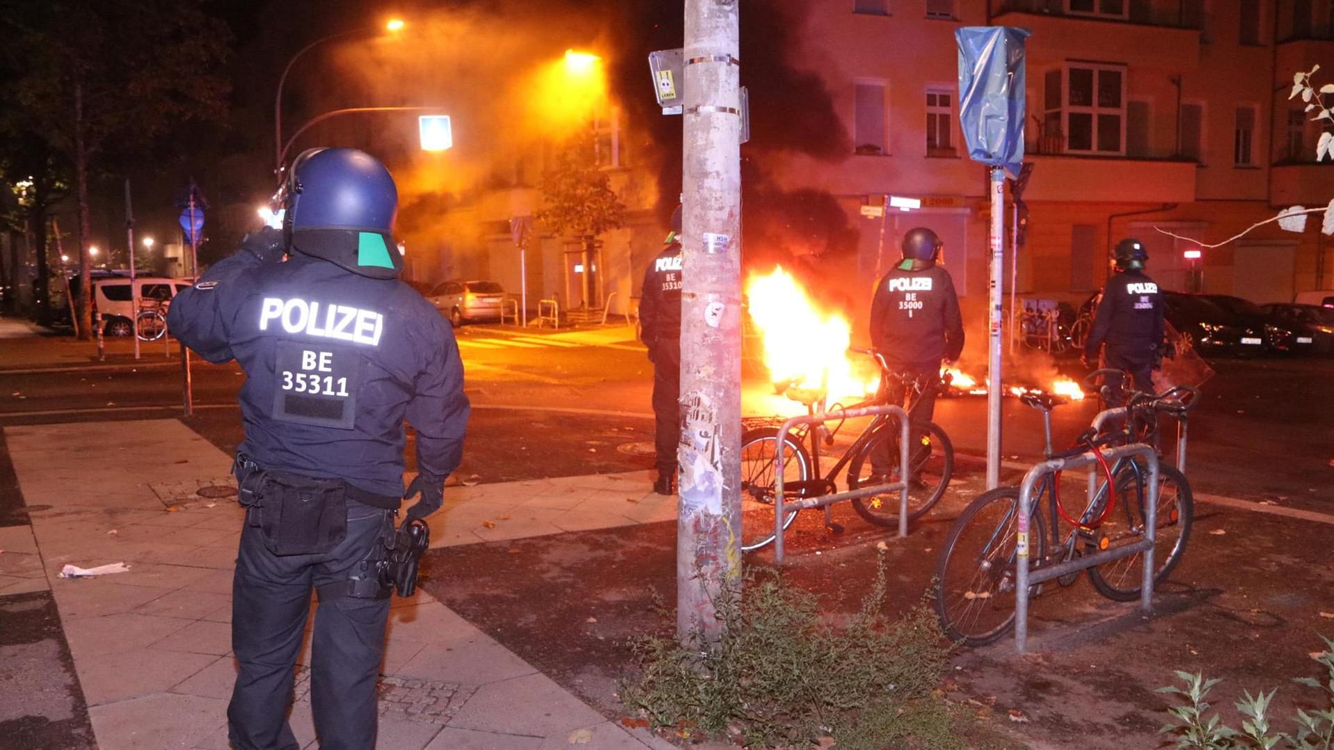 Polizisten stehen neben brennenden Autoreifen: Es kam zu Steinwürfen auf einen Polizeiwagen.