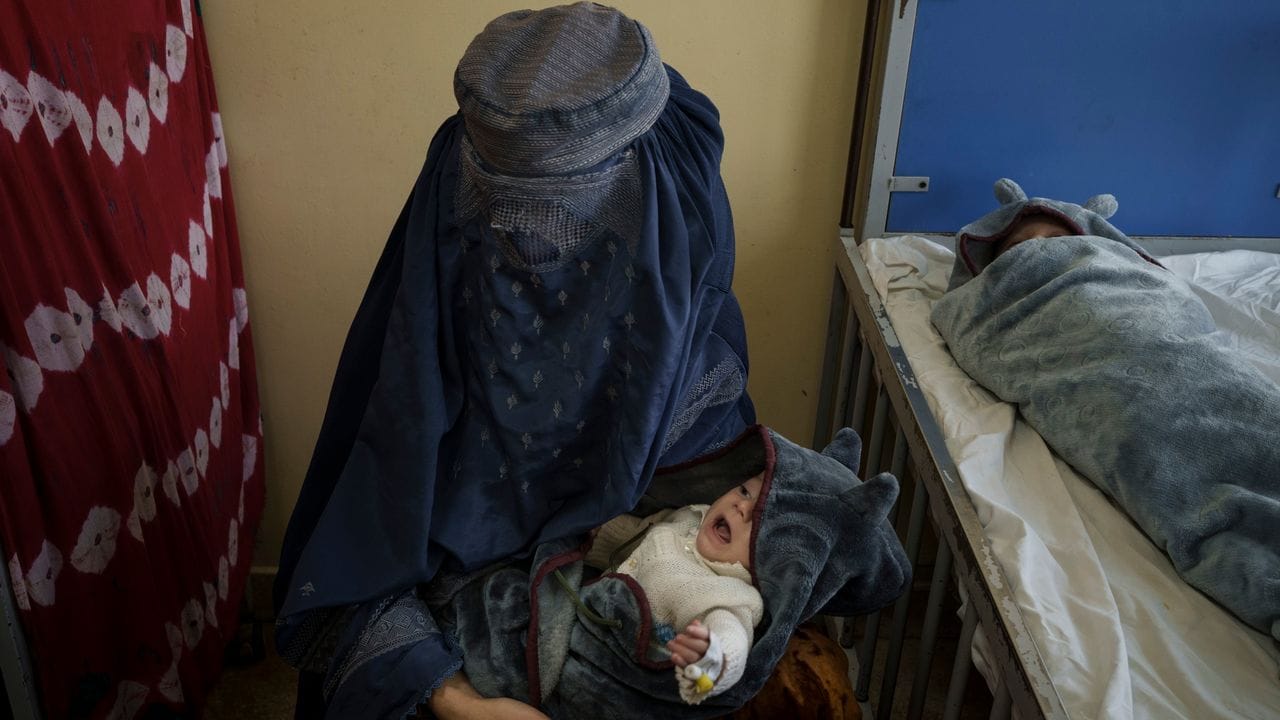 Eine Frau hält eines ihrer beiden Babys, die in Kabul behandelt werden, auf dem Arm.