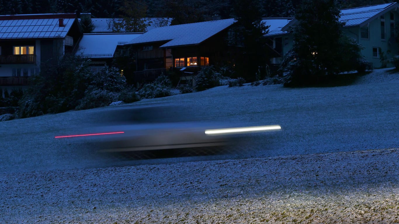 Ein Auto fährt am frühen Morgen im 1.139 Meter hoch gelegenen Ortsteil Oberjoch von Bad Hindelang durch die mit einer dünnen Schneedecke überzogenen Landschaft: In der Nacht gab es den ersten Neuschnee.