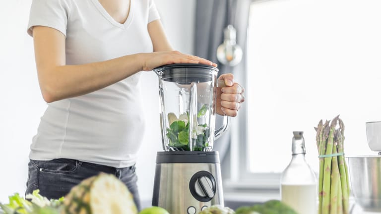 Eine Schwangere zerkleinert Gemüse im Mixer: Normalerweise benötigen Frauen in der Schwangerschaft keine zusätzlichen Eisenpräparate.
