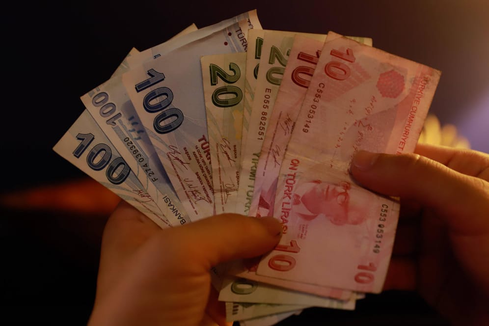 Eine Frau hält türkische Lira in der Hand (Symbolbild): Die Währung gerät immer weiter unter Druck.