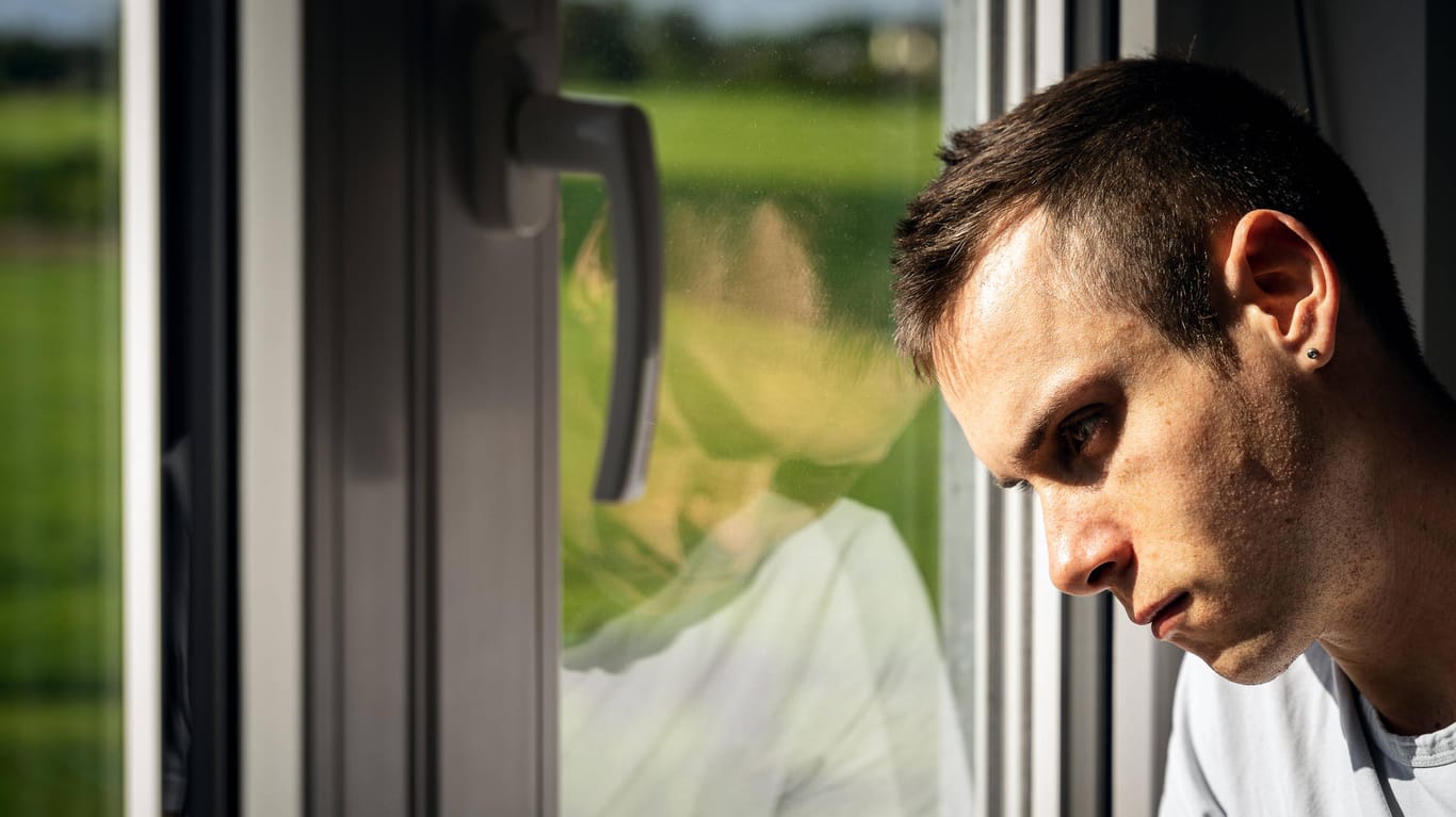 Ein Mann blickt traurig aus dem Fenster: Die Mehrheit der Deutschen sieht die Zukunft pessimistisch.