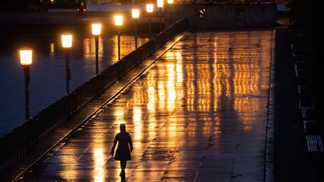 Eine Passantin geht bei Regen über eine Promenade in Hannover