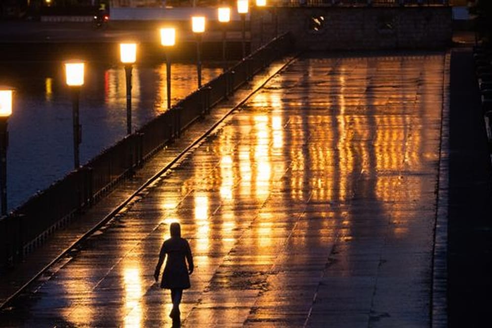 Eine Passantin geht bei Regen über eine Promenade in Hannover