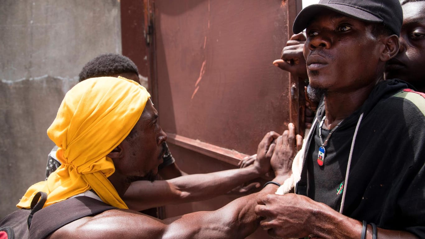 Hungersnot in Haiti: Ein Sicherheitsbeamter hält eine hungrige Menge in Schach.