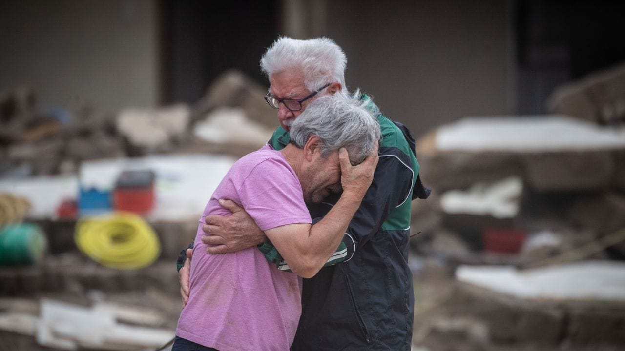 Weinend liegen sich die Brüder Bernd (l) und Gerd Gasper vor ihrem von der Flut zerstörten Elternhaus in Altenahr in den Armen.