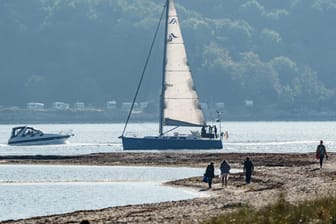 Menschen genießen das ruhige Herbstwetter am Ufer der Kieler Förde: An den Küsten von Nord- und Ostsee wird es am Wochenende eher ungemütlich.