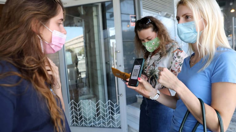 Ein Frau zeigt am Eingang eines Restaurants ihren Impfpass vor: In Israel bekommen nur noch diejenigen ein Impfzertifikat, die auch eine Auffrischungsimpfung erhalten haben.