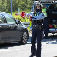 Polizeibeamter mit Polizeikelle: Bei einer Verkehrskontrolle ist es wichtig, sich korrekt zu verhalten.