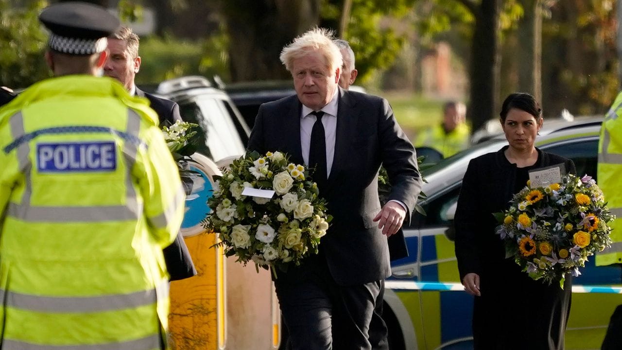Der britische Premier Boris Johnson, gefolgt von Innenministerin Priti Patel mit Blumen in den Händen am Tatort.