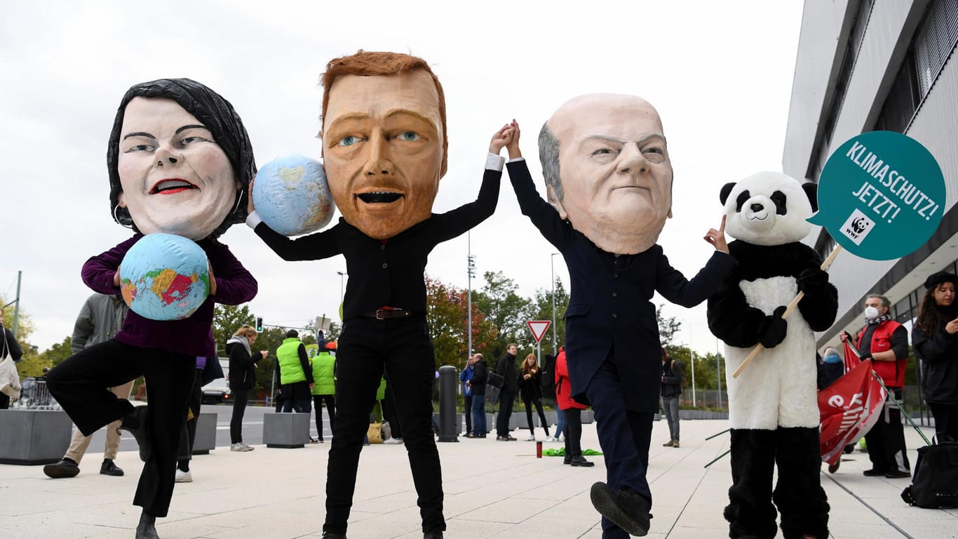 Klimaaktivisten tragen Masken mit den Gesichtern der Ampel-Koalitionäre Anna-Lena Baerbock, Christian Linder und Olaf Scholz vor den Sondierungsgesprächen (Archivbild).