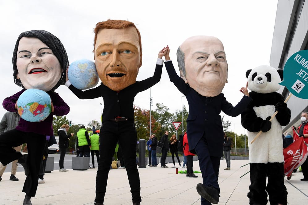 Klimaaktivisten tragen Masken mit den Gesichtern der Ampel-Koalitionäre Anna-Lena Baerbock, Christian Linder und Olaf Scholz vor den Sondierungsgesprächen (Archivbild).