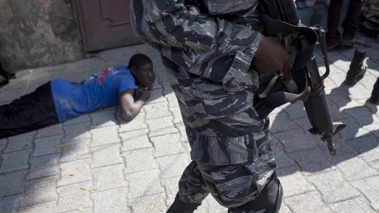 Ein Verdächtiger liegt auf dem Boden in Haiti, bewacht von einem Soldaten (Archivbild). Am Samstag sollen 17 amerikanische Missionare entführt worden sein.