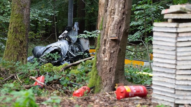 Trümmerteile eines Hubschraubers vom Typ Robinson R44 liegen in einem Wald: Bei dem Vorfall starben drei Menschen.