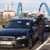 Ein Polizist kontrolliert Reisende aus Polen in Frankfurt (Oder). Wegen vermehrter illegaler Einreisen fordern Polizeigewerkschaftler mehr Kontrollen.