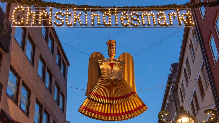 Ein Christkind hängt unter der beleuchteten Aufschrift "Christkindlesmarkt" in der Nürnberger Altstadt (Archivbild): In Nürnberg wird ein neues Christkind gewählt.