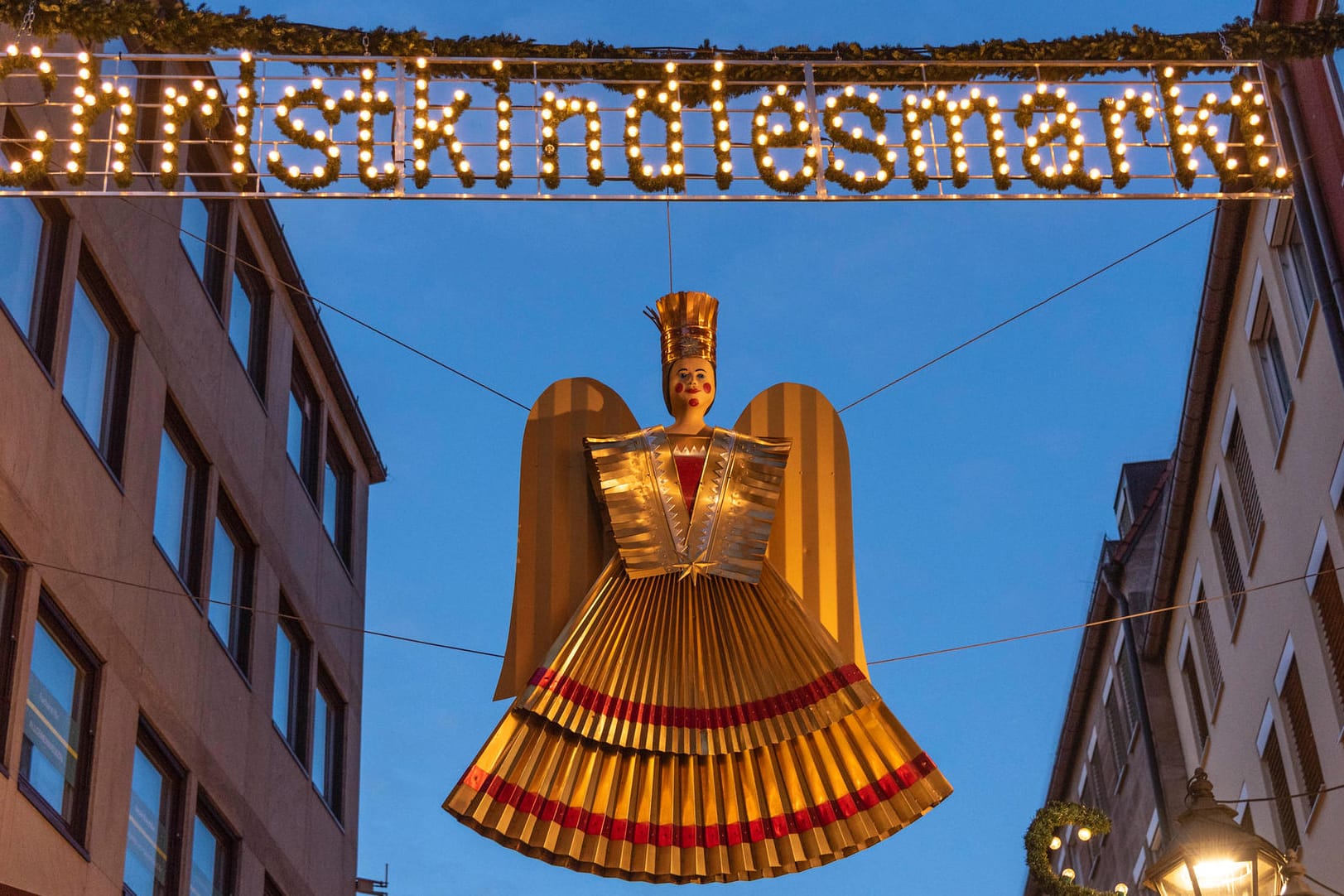 Ein Christkind hängt unter der beleuchteten Aufschrift "Christkindlesmarkt" in der Nürnberger Altstadt (Archivbild): In Nürnberg wird ein neues Christkind gewählt.