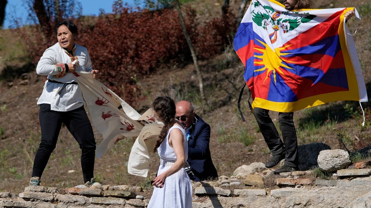Ein Polizist versucht Demonstranten, die eine tibetische Fahne und ein Transparent mit der Aufschrift "Keine völkermörderischen Spiele" zeigen, aufzuhalten.