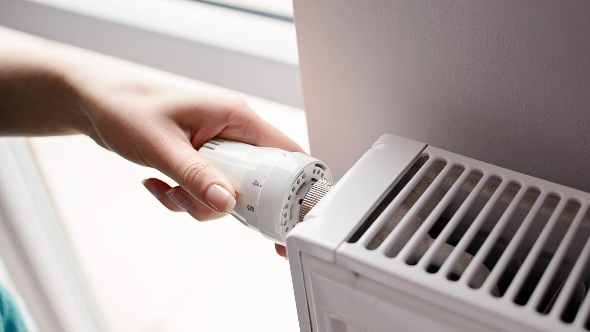 Frau stellt Heizung höher (Symbolbild): Die Mehrheit der Deutschen will den gestiegenen Preisen fürs Heizen mit warmer Kleidung begegnen.