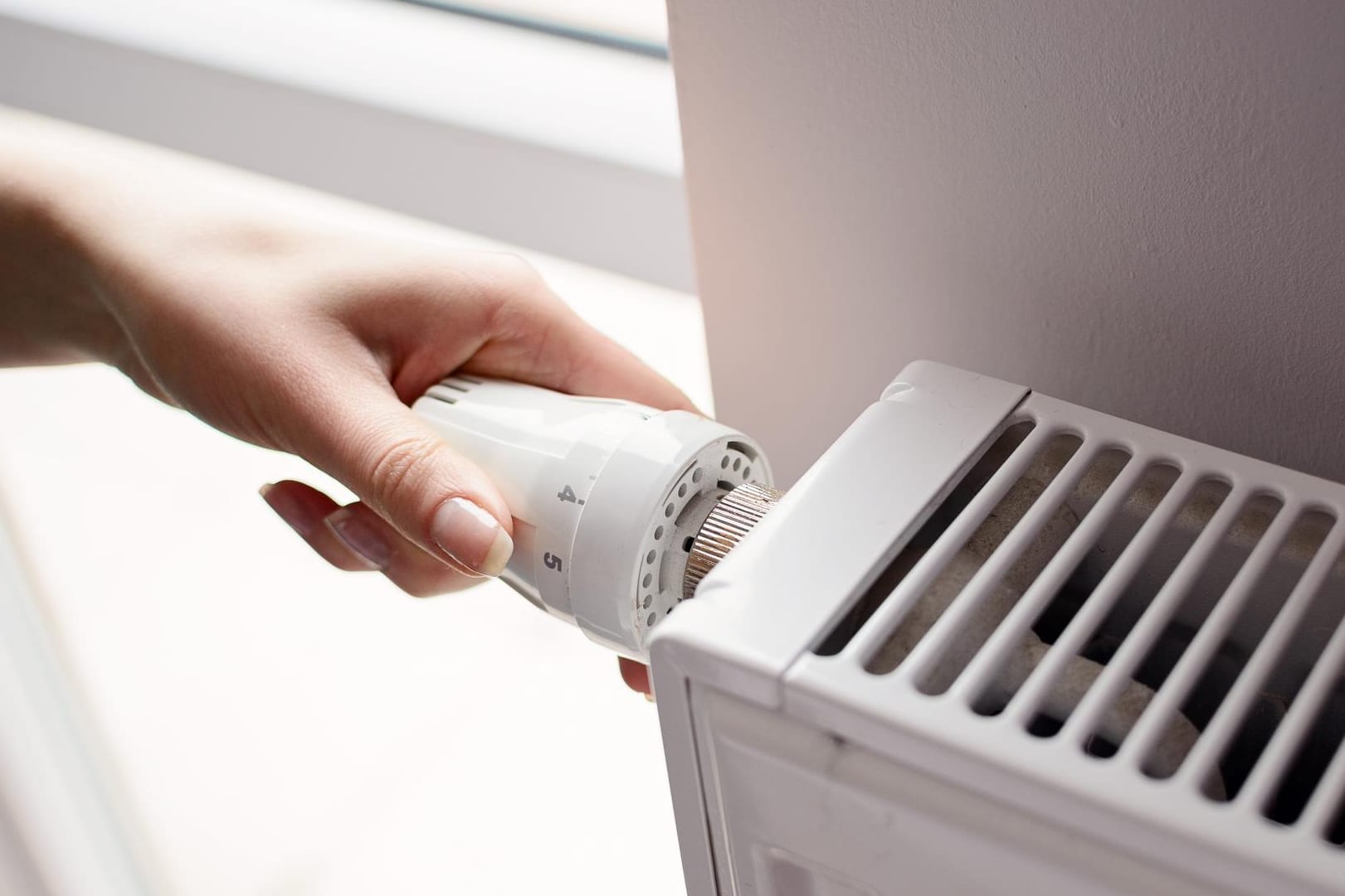 Frau stellt Heizung höher (Symbolbild): Die Mehrheit der Deutschen will den gestiegenen Preisen fürs Heizen mit warmer Kleidung begegnen.