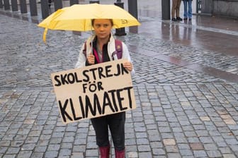 Die Klimaaktivistin Greta Thunberg steht mit einem Schild im Regen (Archivbild): Am Freitag soll es erneute Proteste für mehr Klimaschutz in Berlin geben.