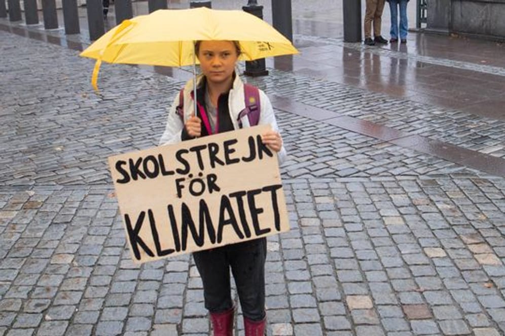 Die Klimaaktivistin Greta Thunberg steht mit einem Schild im Regen (Archivbild): Am Freitag soll es erneute Proteste für mehr Klimaschutz in Berlin geben.