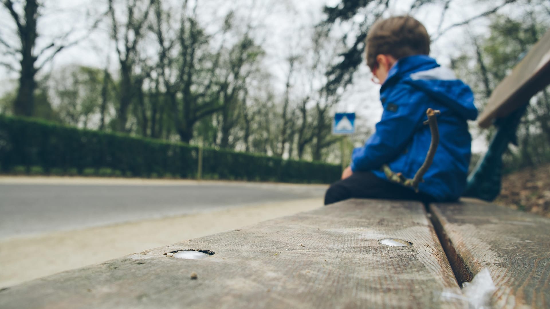 Einsam wirkender Junge auf einer Bank: Kinder mit frühkindlichem Autismus schotten sich von anderen Menschen ab.