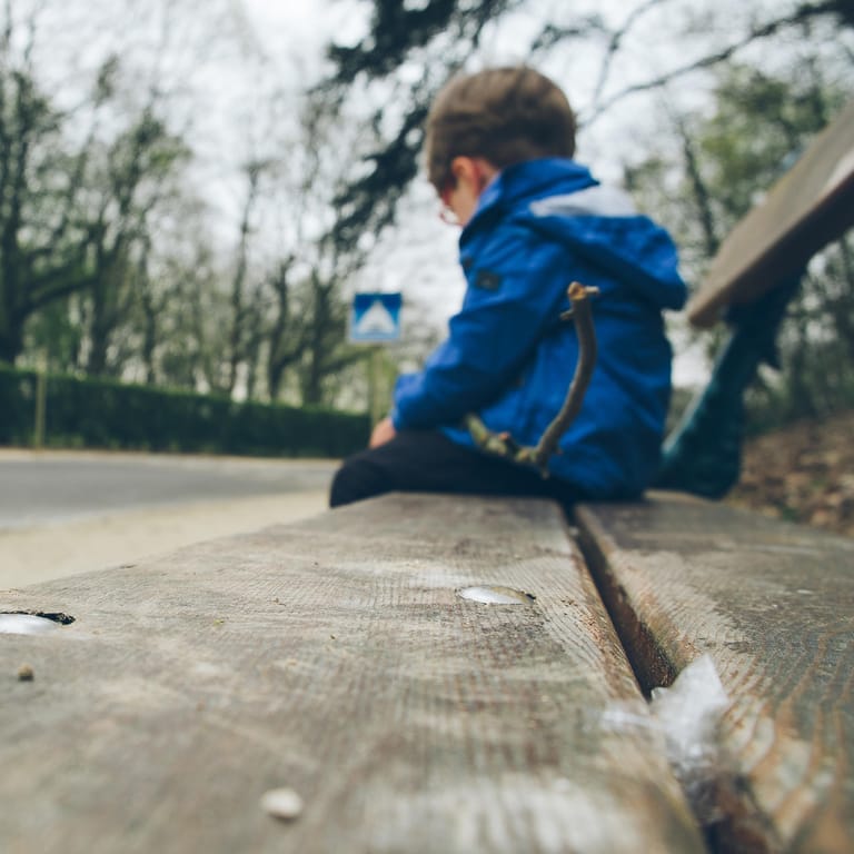 Einsam wirkender Junge auf einer Bank: Kinder mit frühkindlichem Autismus schotten sich von anderen Menschen ab.