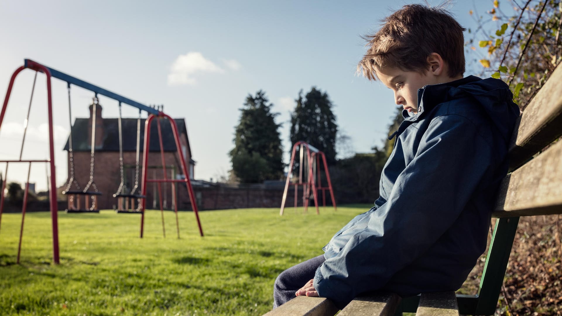 Ein abwesend wirkender Junge auf einer Bank: Kinder mit Kanner-Syndrom können keinen Kontakt zu anderen Menschen herstellen.