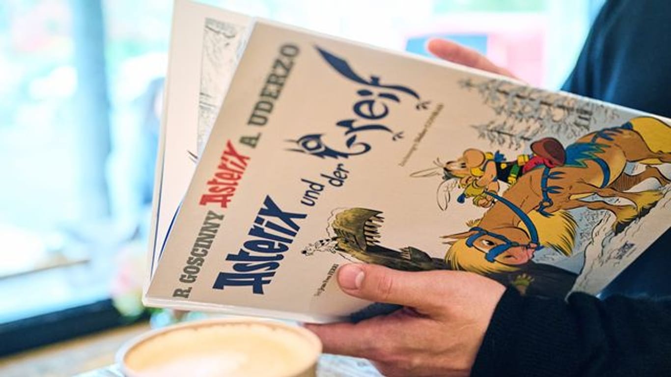 Ein Mann schaut in den neuen Asterix-Band "Asterix und der Greif".