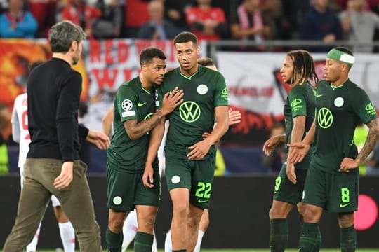 Wolfsburgs Trainer Mark van Bommel (l) geht nach dem Spiel über den Platz zu seinen Spielern.