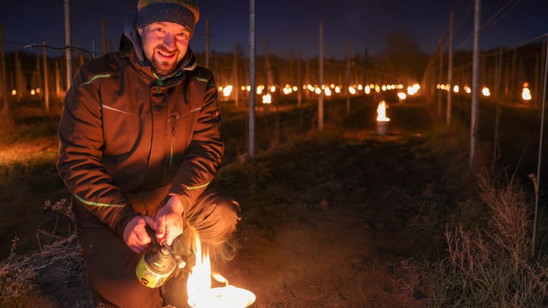 Weinbauleiter Neumeister entfacht ein Weinbergsfeuer im April 2021: Die kleinen Eimer sind mit Paraffin gefüllt, ihre Flammen vertreiben die Minusgrade aus dem Weinberg.
