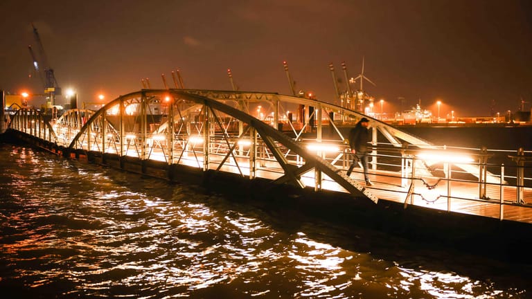 Ein Passant geht bei hohem Wasserstand der Elbe über den Anleger am Fischmarkt: Nach dem ersten Herbststurm ist mit einer weiteren Sturmflut zu rechnen.