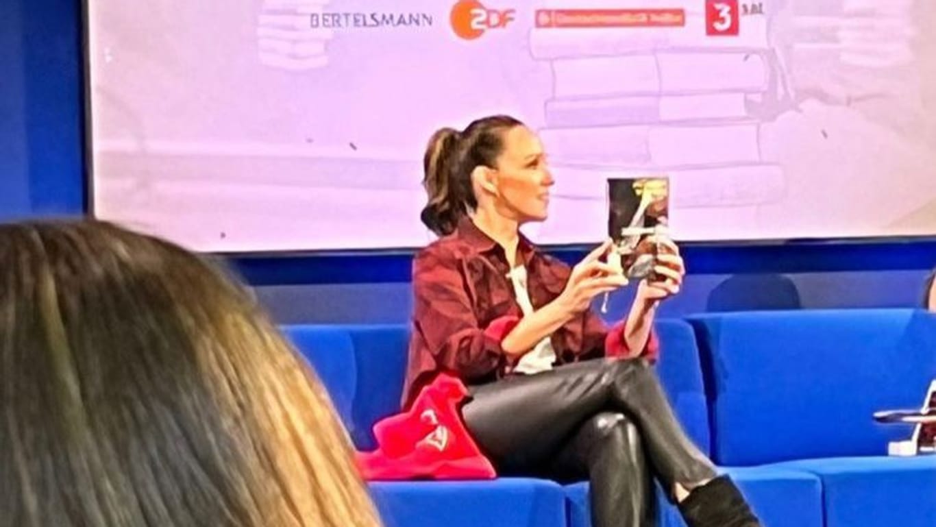 Carolin Kebekus hält am Donnerstagabend das Buch "Schwarzes Herz" in den Händen: Die Komikerin zeigte sich bei der Frankfurter Buchmesse solidarisch mit Autorin Jasmina Kuhnke.