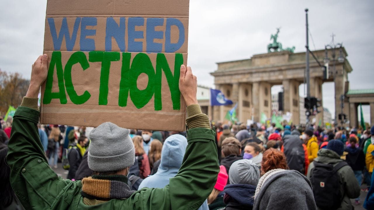 "We need Action": Ein Teilnehmer mit einem Transparent vor dem Brandenburger Tor.