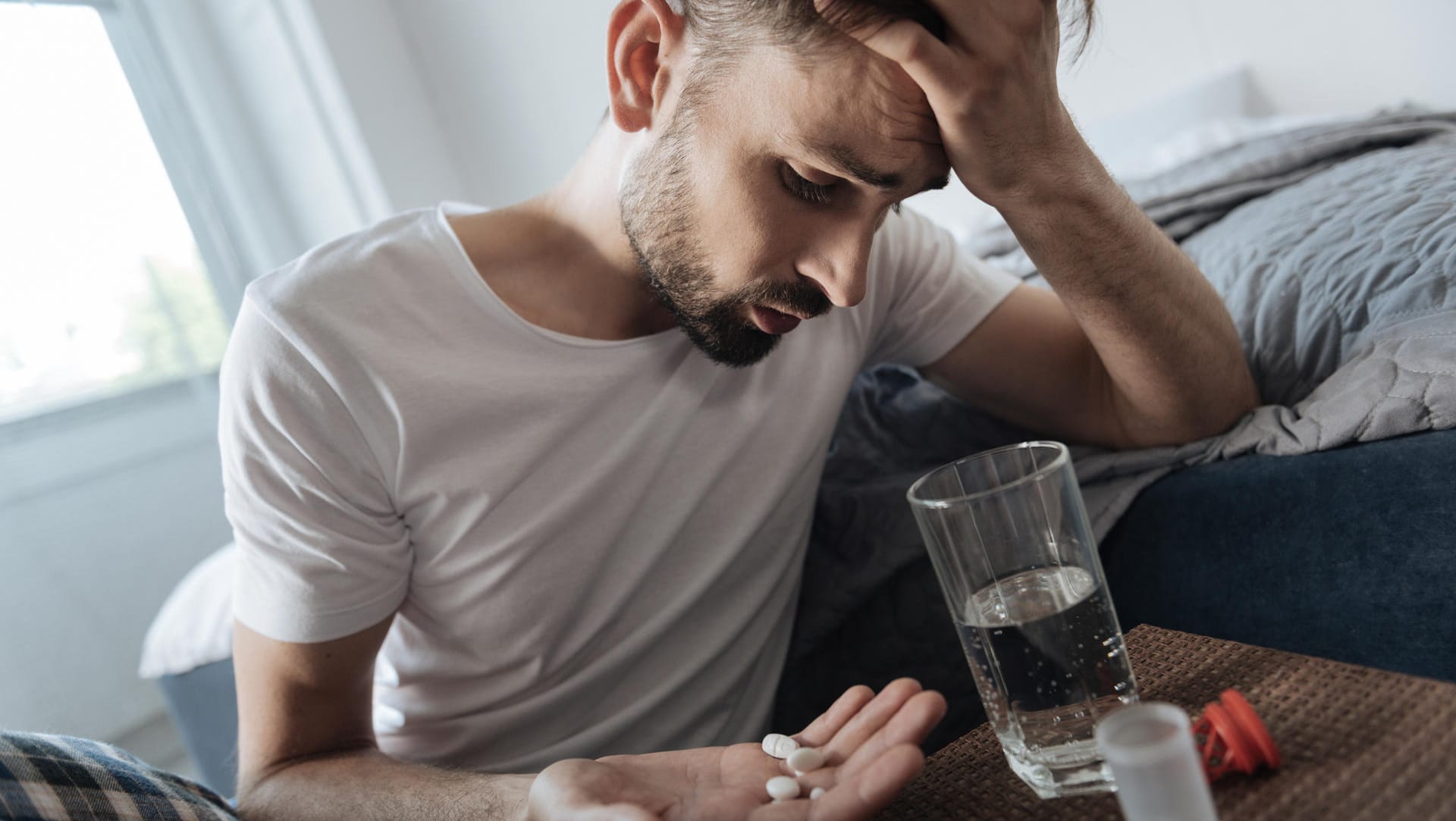 Junger Mann will Tabletten einnehmen: Auch bestimmte Medikamente besitzen ein hohes Suchtpotenzial.