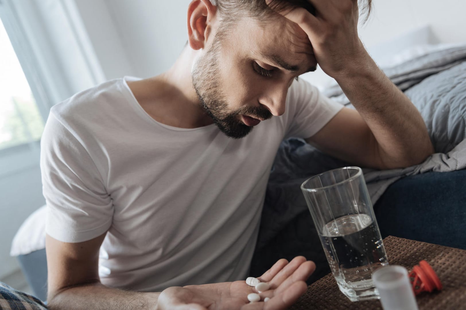 Junger Mann will Tabletten einnehmen: Auch bestimmte Medikamente besitzen ein hohes Suchtpotenzial.